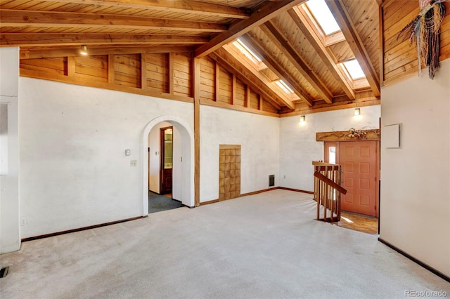 carpeted spare room featuring beam ceiling, a skylight, high vaulted ceiling, and wooden ceiling