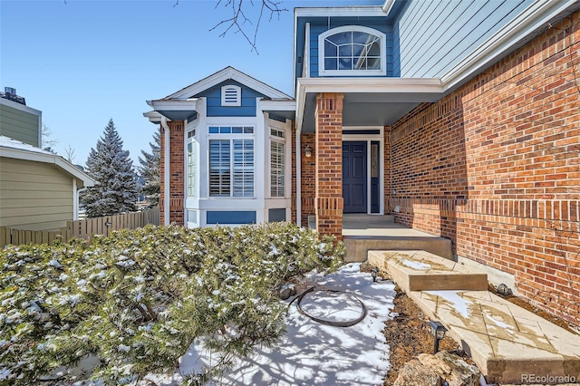 entrance to property featuring brick siding and fence