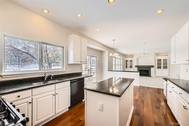 kitchen featuring a center island, black dishwasher, a fireplace, white cabinetry, and a sink