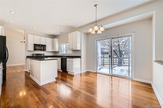 kitchen featuring dark countertops, white cabinets, black appliances, and wood finished floors