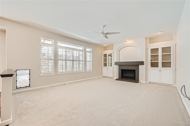 unfurnished living room with carpet floors, a fireplace, baseboards, and a ceiling fan