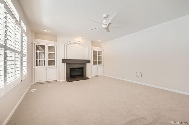 unfurnished living room featuring a ceiling fan, a brick fireplace, visible vents, and baseboards