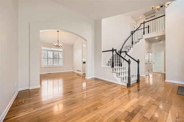 entrance foyer featuring baseboards, visible vents, stairway, wood finished floors, and a notable chandelier