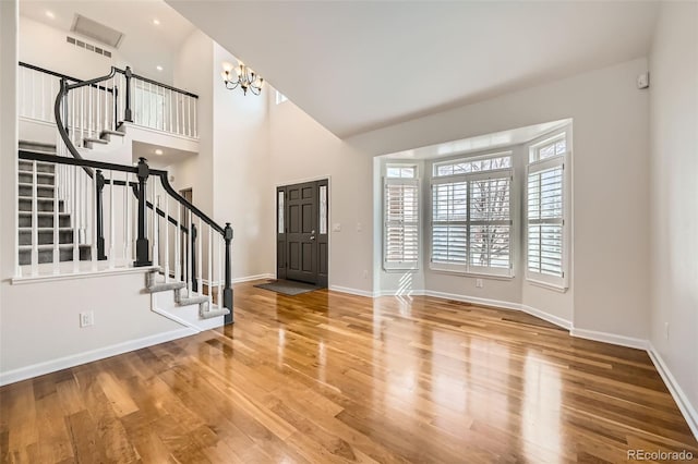 foyer featuring stairway, wood finished floors, a towering ceiling, and baseboards