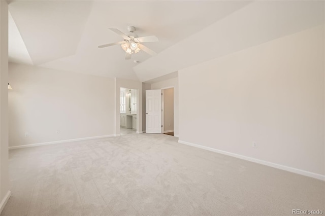 unfurnished bedroom with lofted ceiling, light colored carpet, ensuite bath, and baseboards