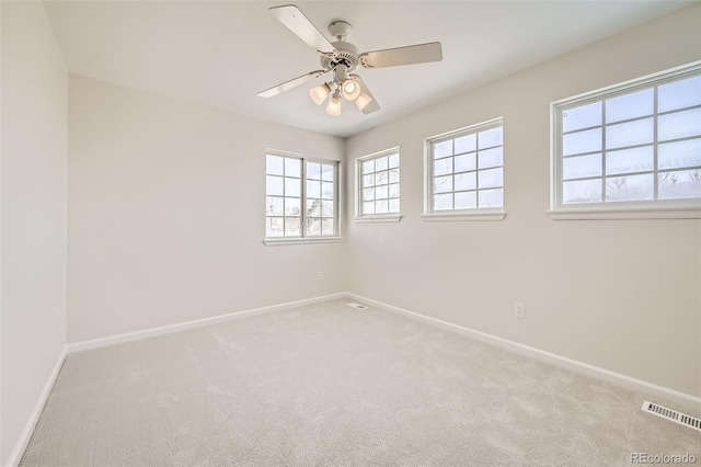 carpeted spare room with a ceiling fan, visible vents, and baseboards