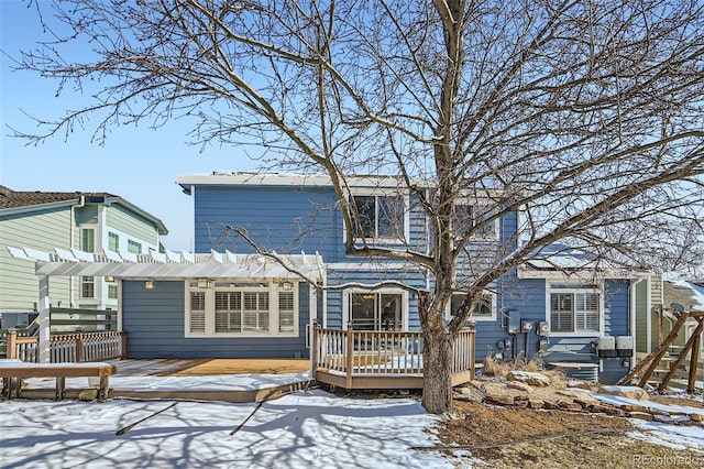 snow covered house featuring a deck, fence, and a pergola