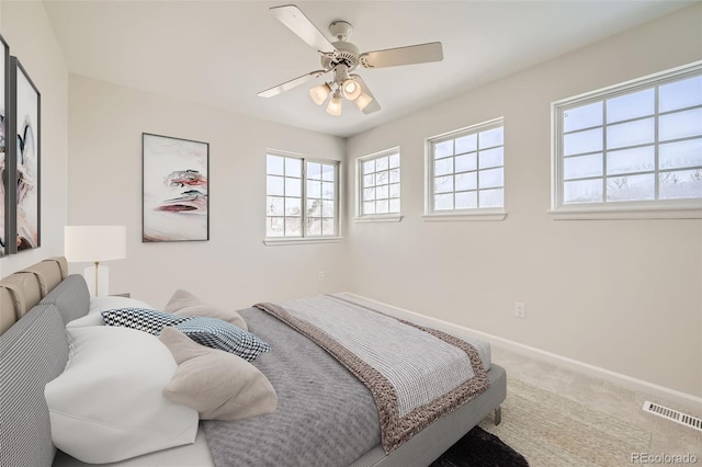 carpeted bedroom with visible vents, ceiling fan, and baseboards