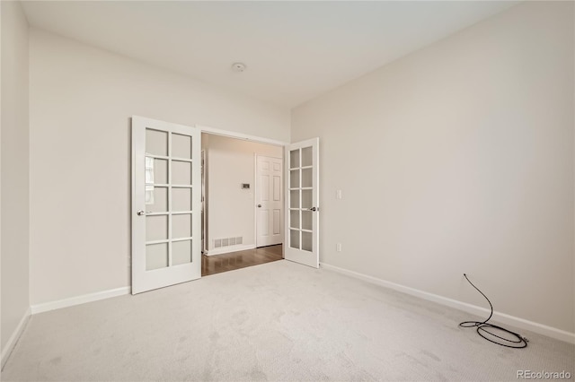 spare room featuring carpet floors, french doors, and baseboards