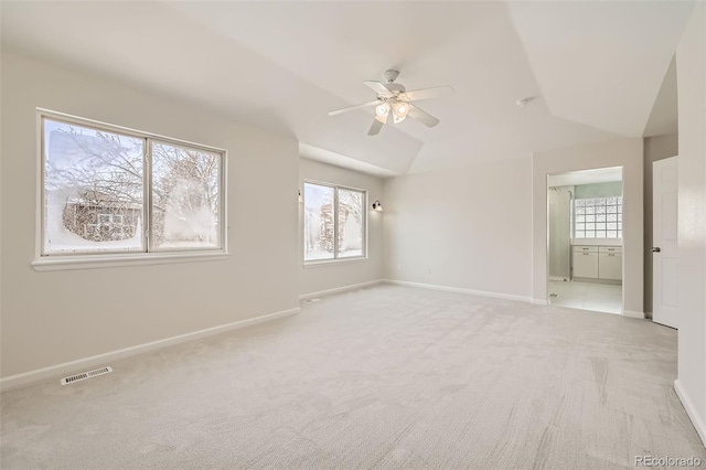 unfurnished room with ceiling fan, lofted ceiling, light colored carpet, visible vents, and baseboards