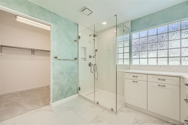 full bathroom featuring a walk in closet, marble finish floor, baseboards, and a marble finish shower