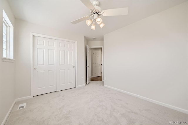 unfurnished bedroom featuring light carpet, baseboards, visible vents, and a closet