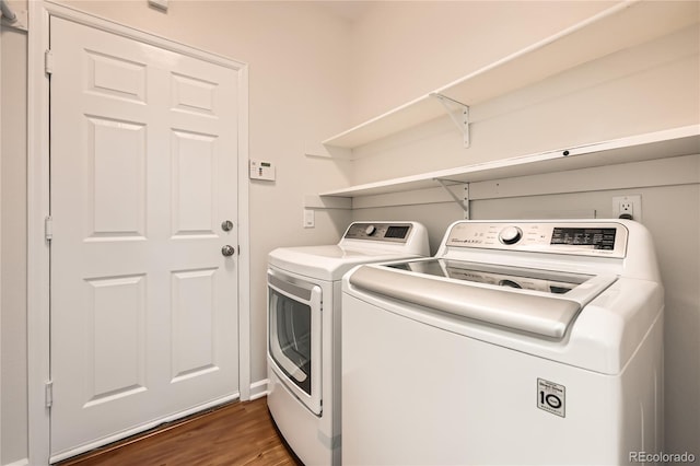 clothes washing area featuring dark wood-type flooring, washer and dryer, and laundry area