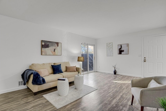 living room featuring wood finished floors, visible vents, and baseboards