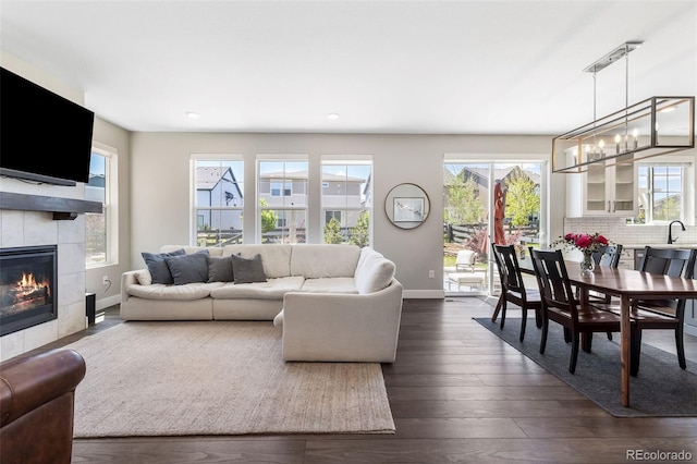 1632 Saddlesmith Pl, Castle Pines, CO 80108 - living area featuring a tile fireplace, a chandelier, dark wood-style flooring, and recessed lighting