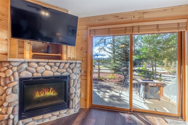 doorway to outside with wooden walls, wood finished floors, and a stone fireplace