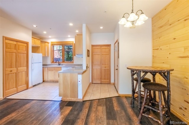 kitchen with a peninsula, light wood finished floors, light brown cabinets, and freestanding refrigerator