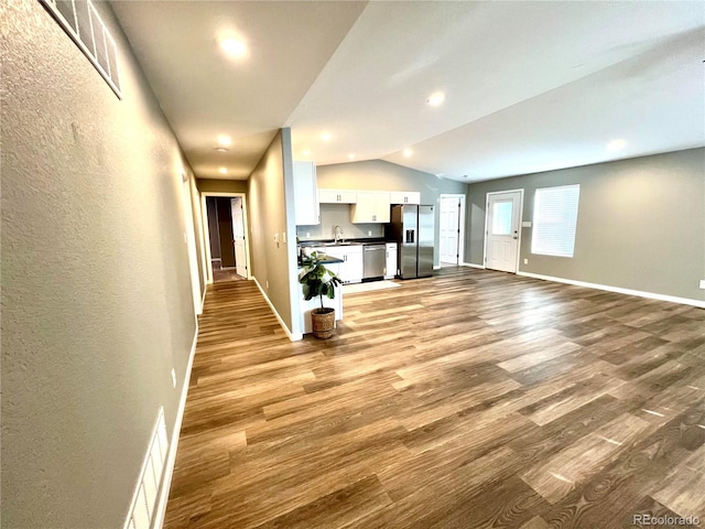 interior space with lofted ceiling, sink, and light hardwood / wood-style flooring