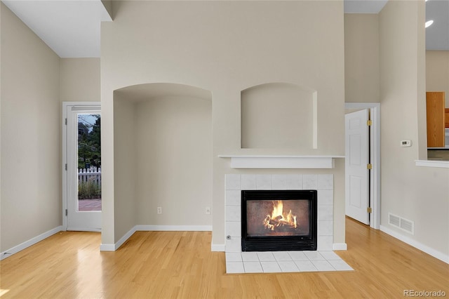 11268 Grove St Unit I, Westminster, CO 80031 - unfurnished living room with wood finished floors, a tiled fireplace, and a towering ceiling