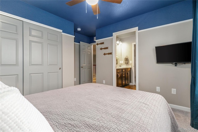 carpeted bedroom with ceiling fan, ensuite bathroom, sink, and a closet