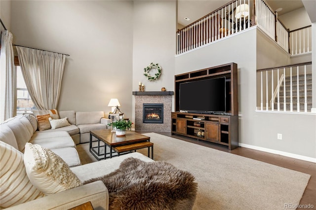 living room with dark wood-type flooring, a fireplace, and a towering ceiling