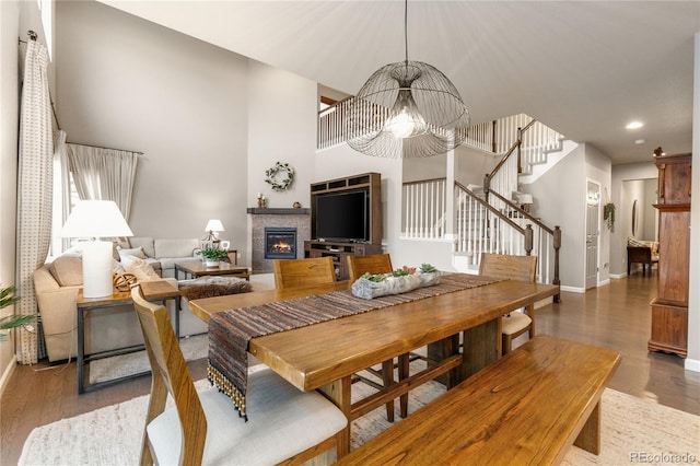 dining space with a notable chandelier, dark wood-type flooring, a fireplace, and a high ceiling