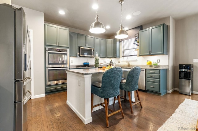 kitchen with dark wood-type flooring, stainless steel appliances, a center island, light stone counters, and decorative light fixtures