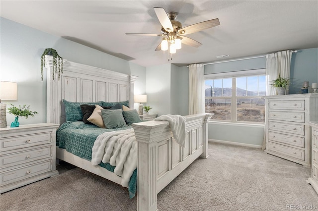 bedroom with baseboards, a mountain view, a ceiling fan, and light colored carpet