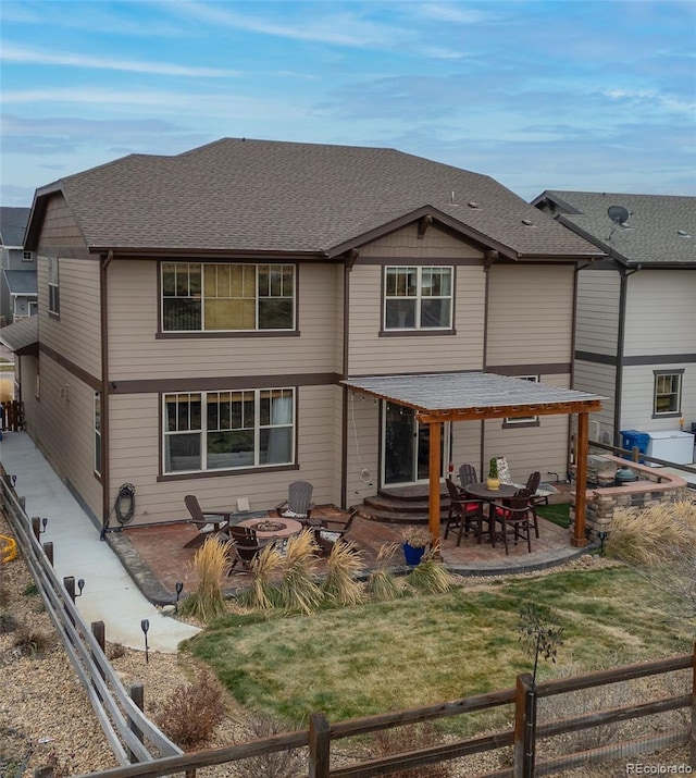 rear view of house with a patio area, a shingled roof, and a fire pit