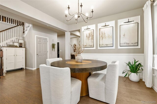 dining area featuring a notable chandelier, stairs, baseboards, and wood finished floors