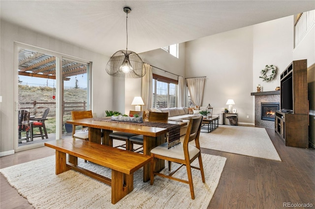 dining room with a glass covered fireplace, a high ceiling, baseboards, and wood finished floors