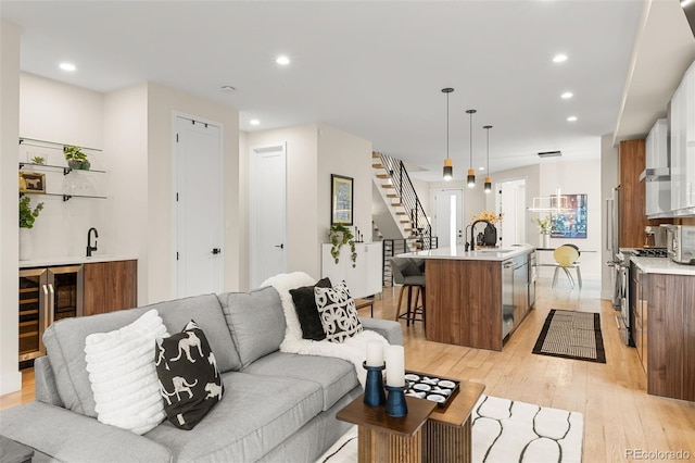 living room with light hardwood / wood-style flooring, wet bar, and beverage cooler