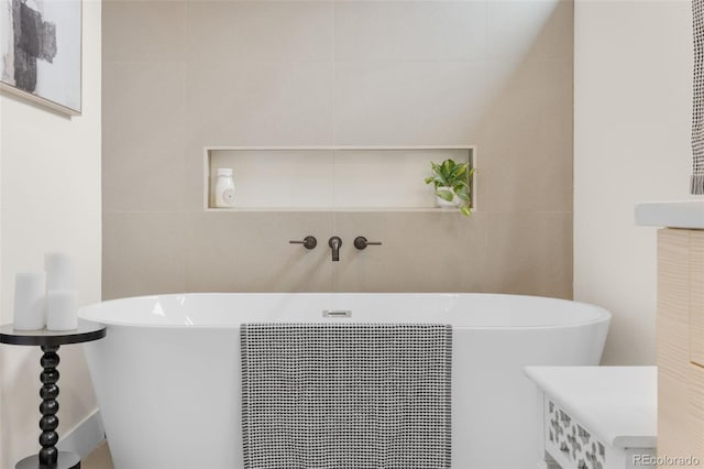 bathroom featuring a bath and tile walls