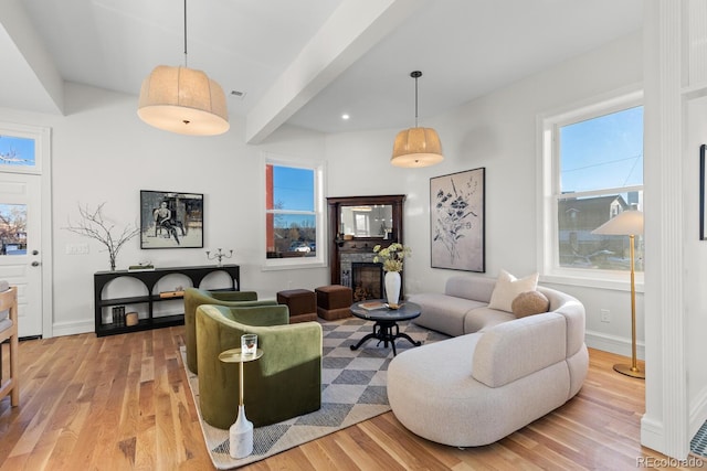 living room featuring visible vents, a fireplace, light wood-style flooring, and baseboards