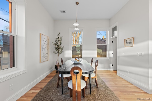 dining area with light wood-style flooring, visible vents, and baseboards