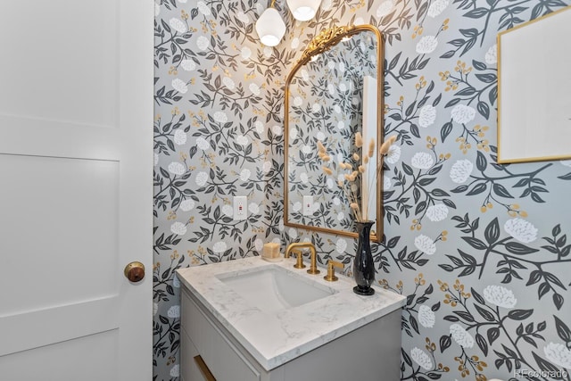 half bath featuring vanity and wallpapered walls