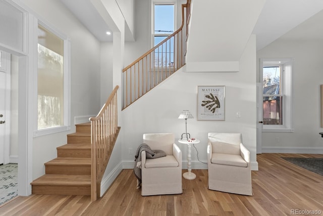 interior space with baseboards, a high ceiling, stairway, and wood finished floors