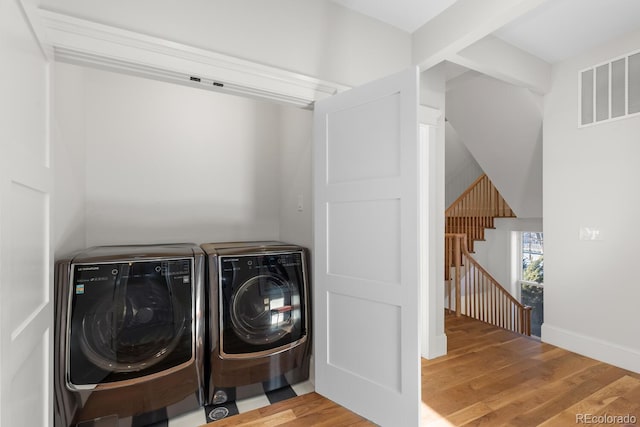 washroom featuring visible vents, wood finished floors, washer and dryer, laundry area, and baseboards