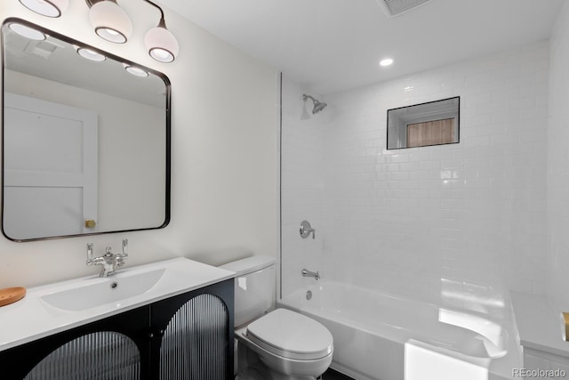 full bathroom featuring vanity, tiled shower / bath combo, and toilet