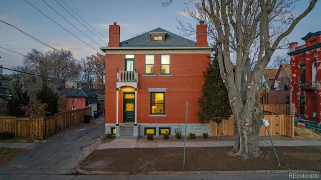 view of front facade featuring brick siding, a chimney, and fence