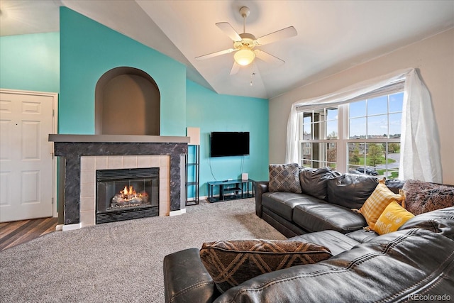 living area featuring lofted ceiling, ceiling fan, and a tiled fireplace