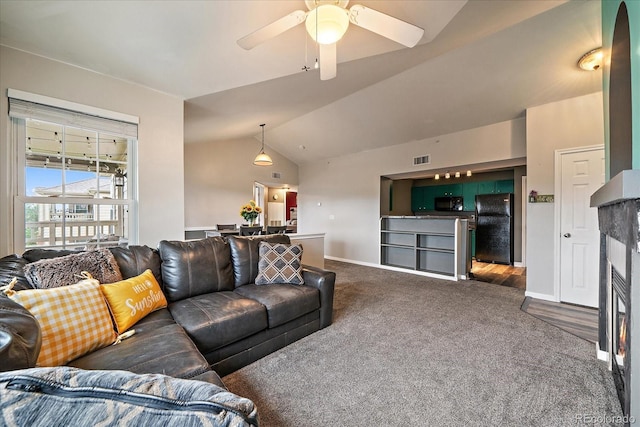 living area featuring dark colored carpet, vaulted ceiling, ceiling fan, and baseboards