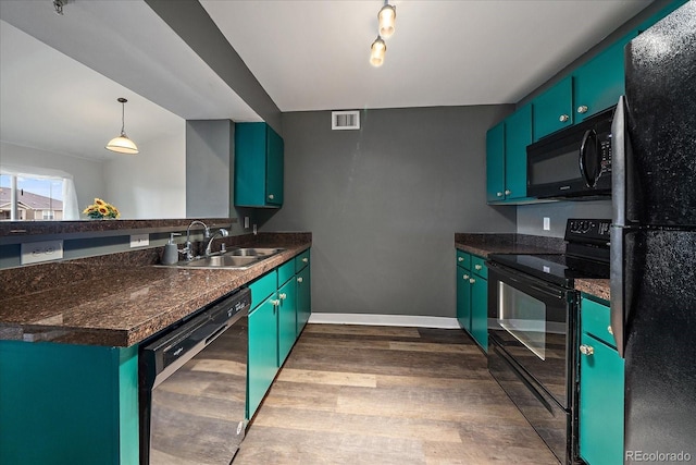 kitchen with black appliances, dark wood-type flooring, a sink, dark countertops, and a peninsula