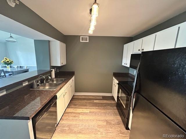 12931 Ironstone Way Unit 303, Parker, CO 80134 - kitchen featuring black appliances, a sink, light wood finished floors, a peninsula, and white cabinetry