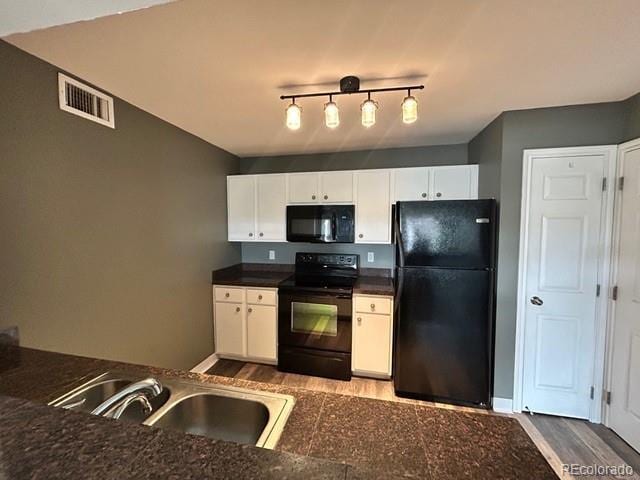12931 Ironstone Way Unit 303, Parker, CO 80134 - kitchen featuring black appliances, wood finished floors, dark countertops, a sink, and white cabinets