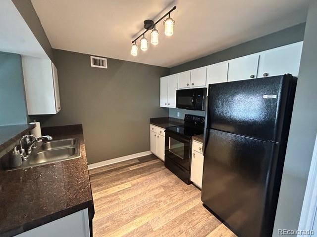 12931 Ironstone Way Unit 303, Parker, CO 80134 - kitchen with black appliances, a sink, dark countertops, white cabinets, and light wood finished floors