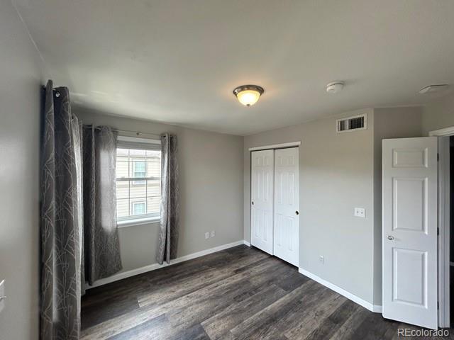 12931 Ironstone Way Unit 303, Parker, CO 80134 - unfurnished bedroom featuring dark wood finished floors, baseboards, and a closet