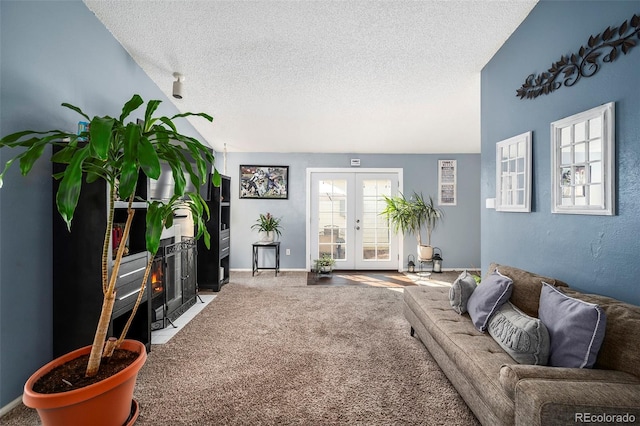 carpeted living room with french doors, vaulted ceiling, and a textured ceiling