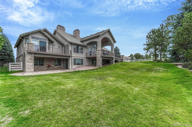 rear view of property featuring a lawn, a patio, and a balcony