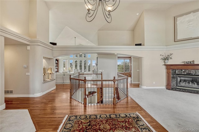 hall featuring high vaulted ceiling, hardwood / wood-style floors, and a notable chandelier